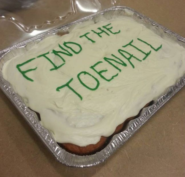 Homemade cake with "Find the Toenail" written on it in frosting.